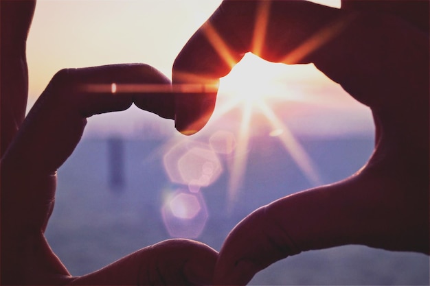 Imagen recortada de una persona haciendo forma de corazón contra el cielo