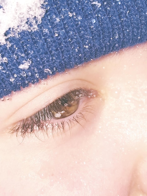 Imagen recortada de una persona con un sombrero de punto cubierto de nieve