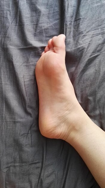 Foto imagen recortada de una pierna en la cama