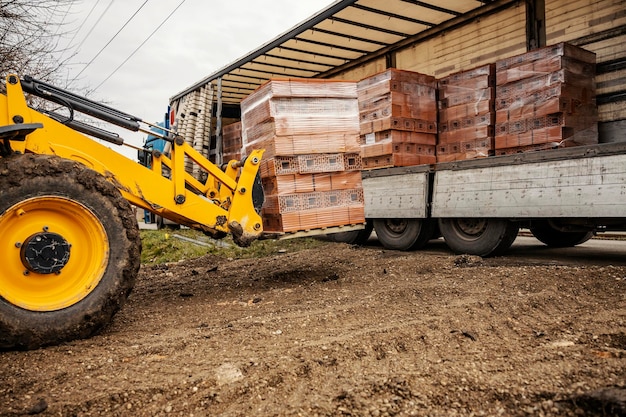 Imagen recortada de un polipasto levantando ladrillos en el sitio de construcción