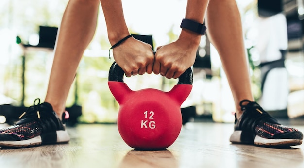 Imagen recortada de primer plano de una joven mujer fitness haciendo ejercicio de swing con pesas rusas como parte de un entrenamiento de fitness en el gimnasio o club de fitness