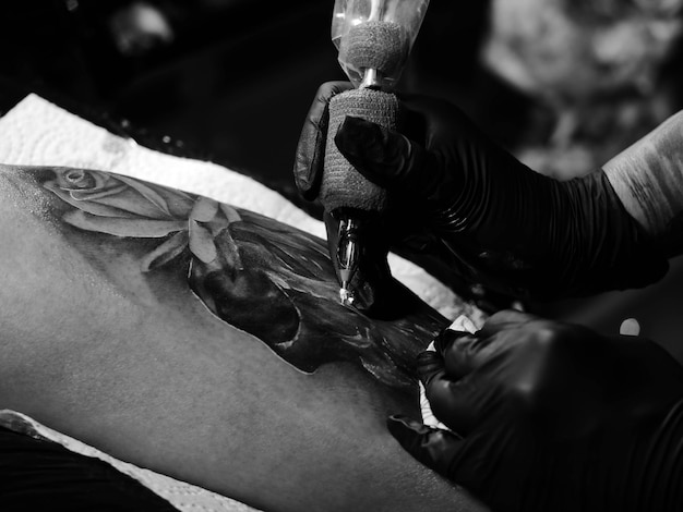 Foto imagen recortada de un tatuador haciendo un tatuaje en un cliente