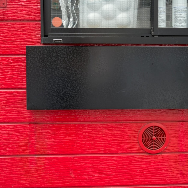 Foto imagen recortada de una ventana negra en una pared roja