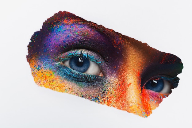 Imagen de recorte de ojos femeninos con maquillaje de polvo colorido. Hermosa modelo con maquillaje de arte creativo. Maquillaje splash colorido abstracto. Festival de holi