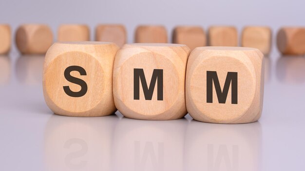 La imagen representa tres bloques de madera con las letras SMM en foco que se reflejan en la superficie de la mesa