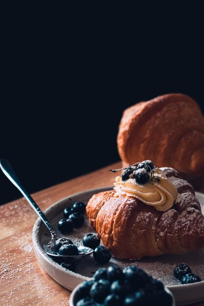 Foto imagen de un restaurante de comida sabrosos croissants cubiertos con crema de azúcar glas y jugo de arándanos xd