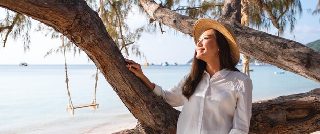 Imagen de retrato de una hermosa joven asiática con el árbol junto al mar