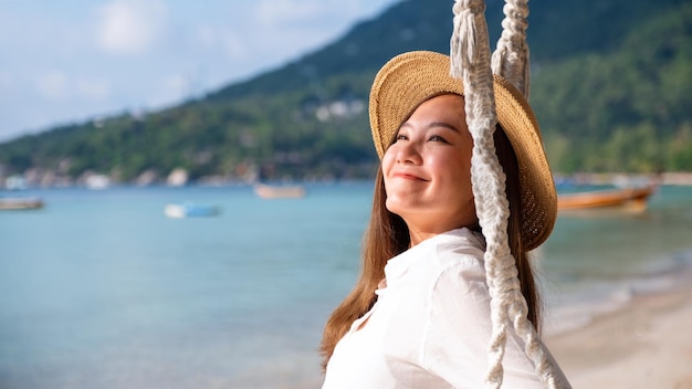 Imagen de retrato de una hermosa joven asiática con columpio junto al mar