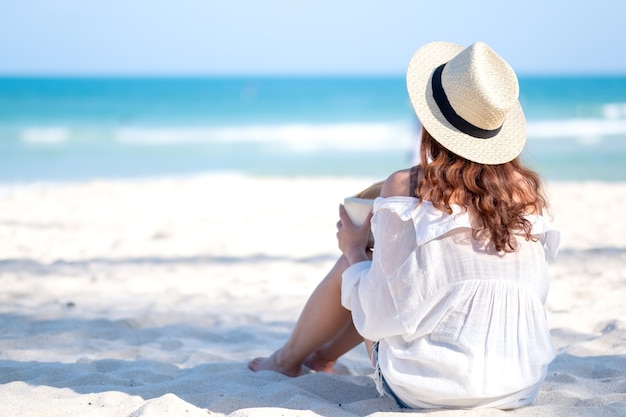 Imagen de retrato de una hermosa mujer asiática disfruta de sentarse y beber jugo de coco en la playa