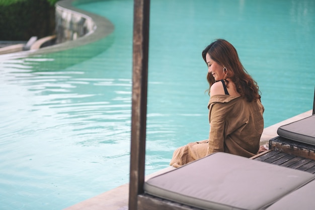 Foto imagen de retrato de una hermosa mujer asiática disfrutó sentado junto a la piscina