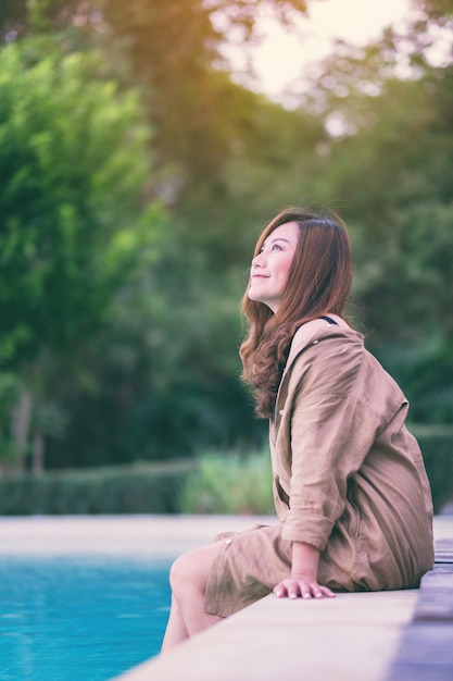 Imagen de retrato de una hermosa mujer asiática disfrutó sentado junto a la piscina