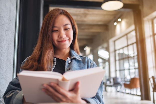 Imagen de retrato de una joven y hermosa mujer asiática sentada y leyendo un libro