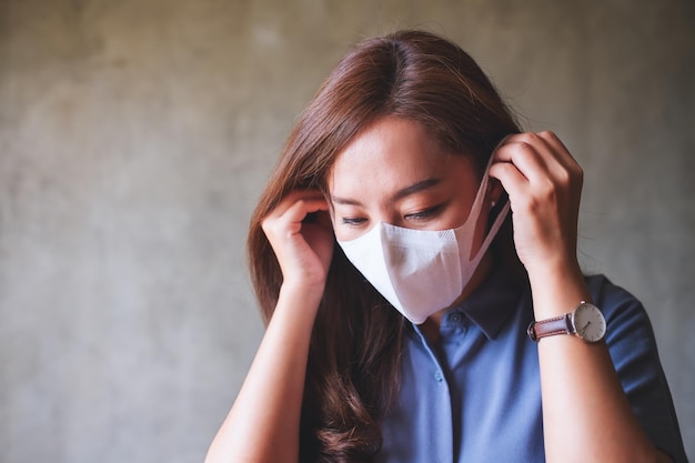 Imagen de retrato de una mujer asiática poniéndose una máscara facial protectora para el concepto de atención médica y Covid19