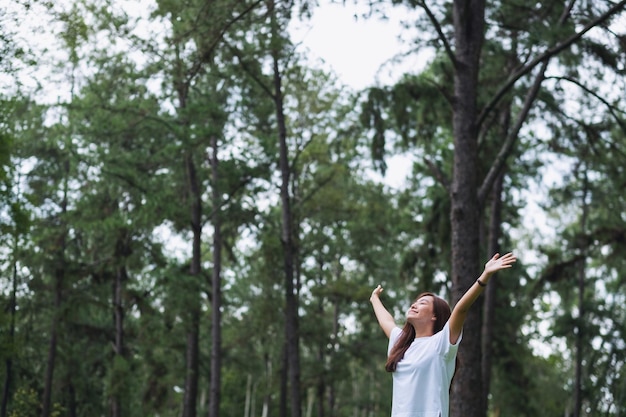 Foto imagen de retrato de una mujer feliz con los brazos levantados en el parque