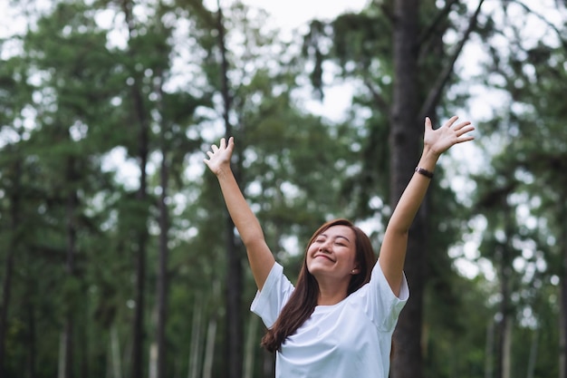 Imagen de retrato de una mujer feliz con los brazos levantados en el parque