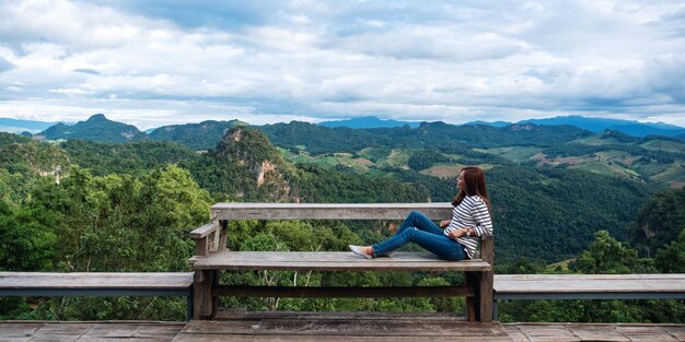 Imagen de retrato de una viajera sentada y mirando una hermosa vista de la montaña y la naturaleza