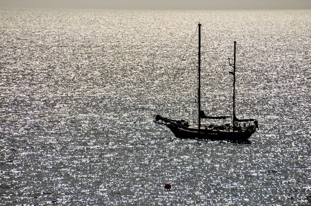 Imagen de retroiluminación de un barco de silueta en el océano