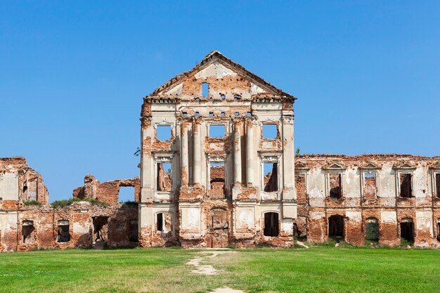 Imagen de ruinas antigua fortaleza, cielo azul y pasto verde en el césped