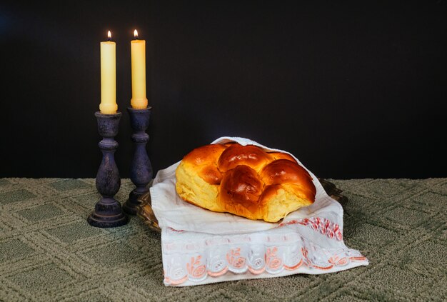 Foto imagen sabática. pan challah, candelas en mesa de madera. superposición de brillo