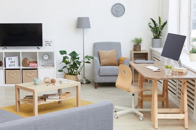 Imagen de sala de estar moderna con TV y mesa con computadora en la casa