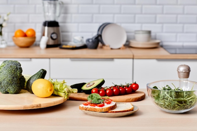 Imagen de sándwiches con verduras en un plato con otras verduras frescas en una tabla de madera preparando f