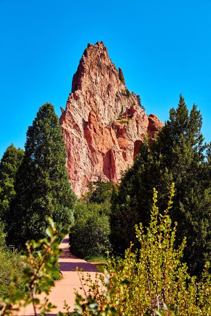 Imagen de sendero en campo verde que conduce a un gran pilar de roca roja