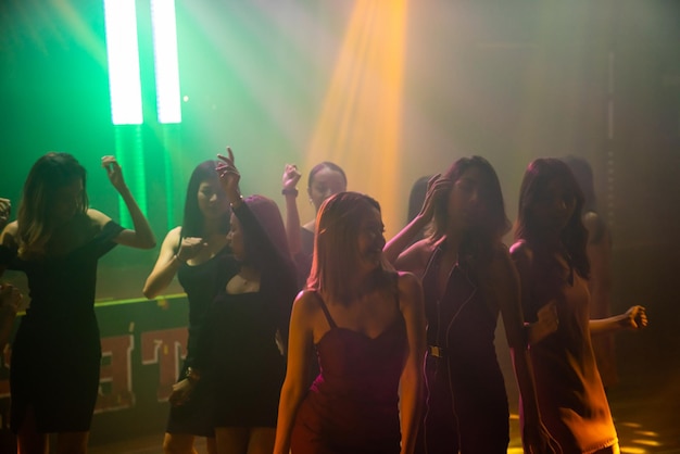 Imagen de la silueta de la gente baila en la discoteca al ritmo de la música de DJ en el escenario