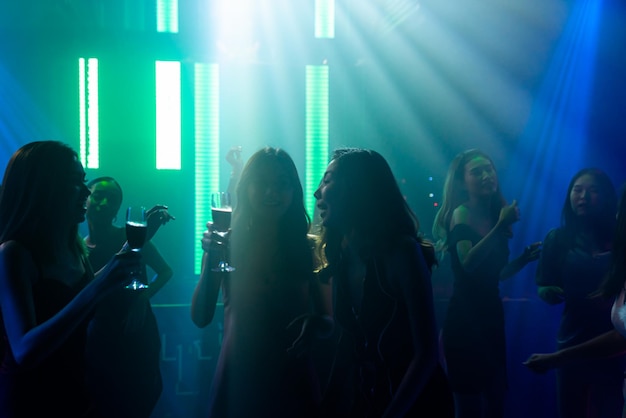 Imagen de silueta de gente bailando en discoteca con música de DJ en el escenario