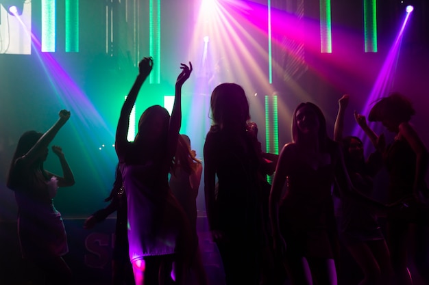 Foto imagen de silueta de gente bailando en discoteca con música de dj en el escenario