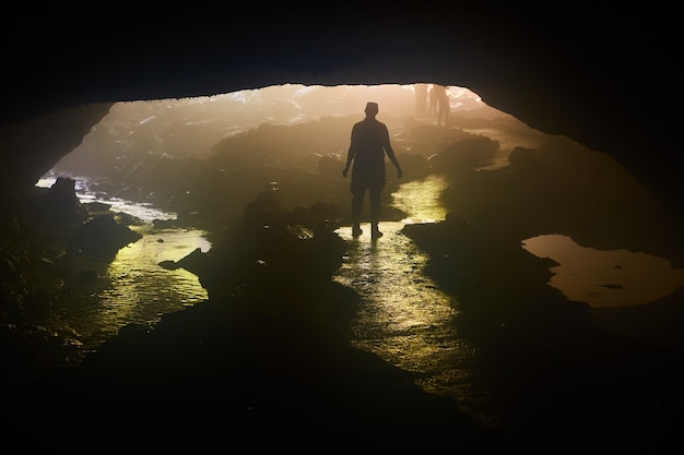 Imagen de silueta humana de pie en la apertura de la cueva