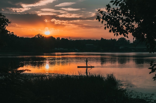 Imagen de la silueta de una niña en una tabla de remo en un río antes del atardecer Sup surf