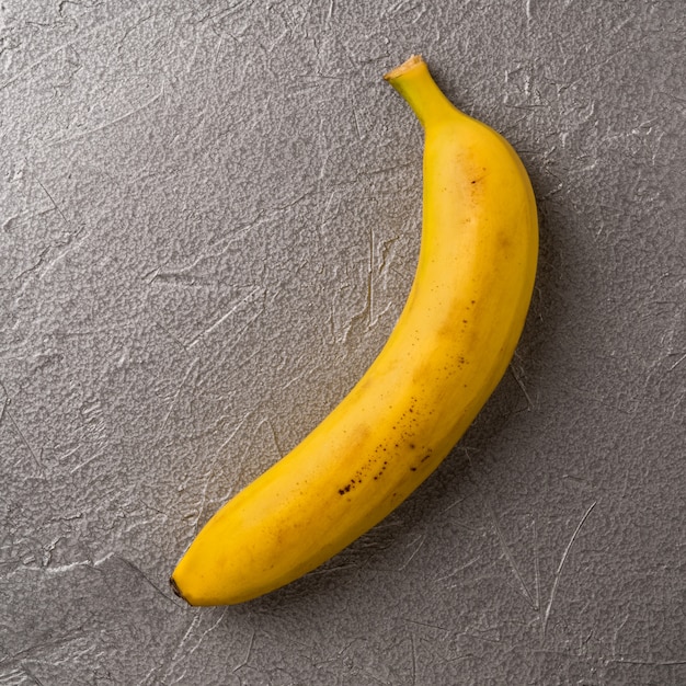 Imagen simple de plátano amarillo maduro solo sobre fondo gris metálico