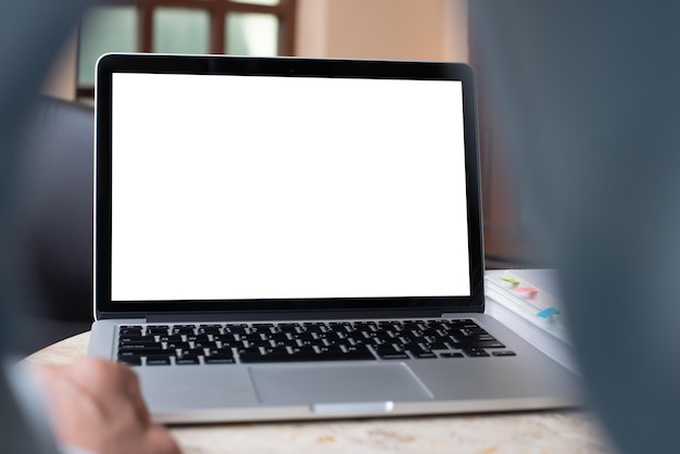 Imagen simulada de una computadora portátil de pantalla blanca en blanco en el escritorio con un hombre de negocios trabajando en la oficina vista frontal Se puede usar para diseño web o exhibición de productos