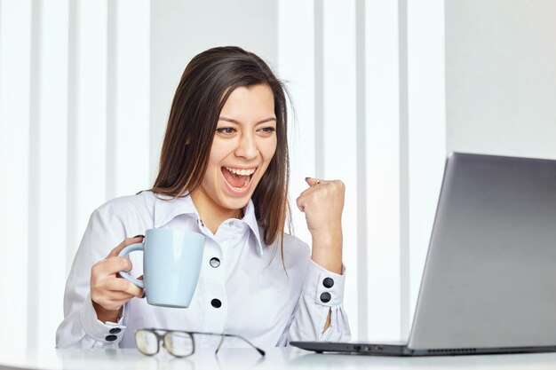 Foto imagen sincera de una mujer de negocios tomando café mientras trabaja en la oficina