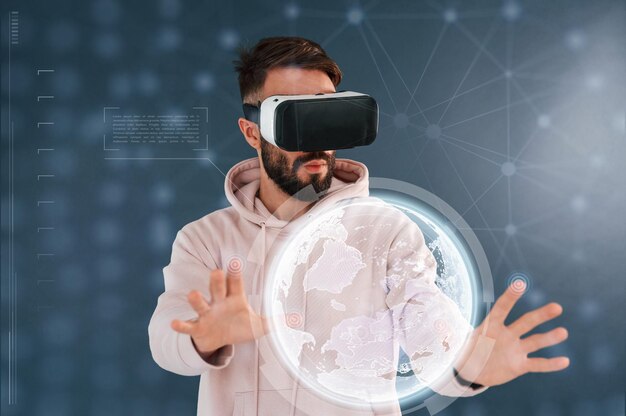 Imagen de la Tierra en gafas de realidad virtual Un hombre guapo está en el estudio contra un fondo azul