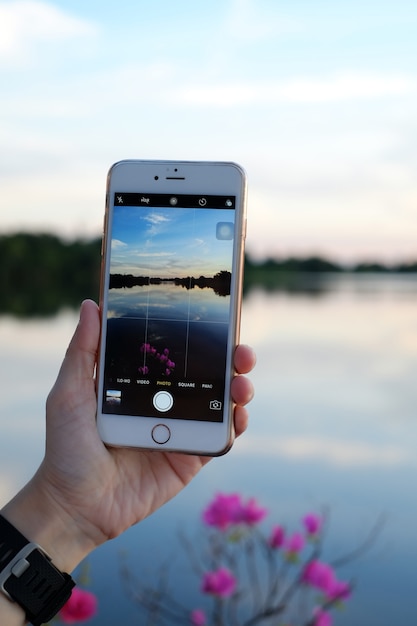 Imagen de toma de la mano humana de la naturaleza del lago con teléfono móvil