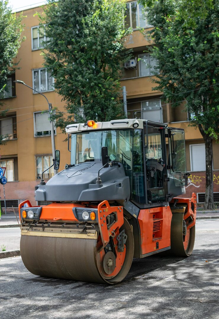 Imagen del tractor naranja con cilindro para pavimentar asfalto en la carretera