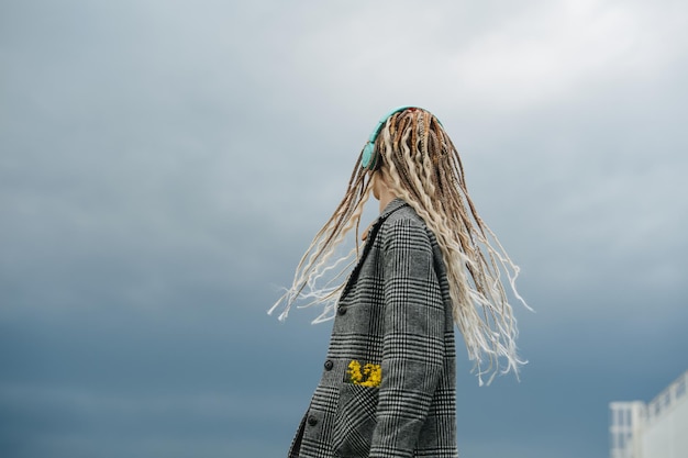 Imagen trasera de una adolescente con rastas mirando a lo lejos