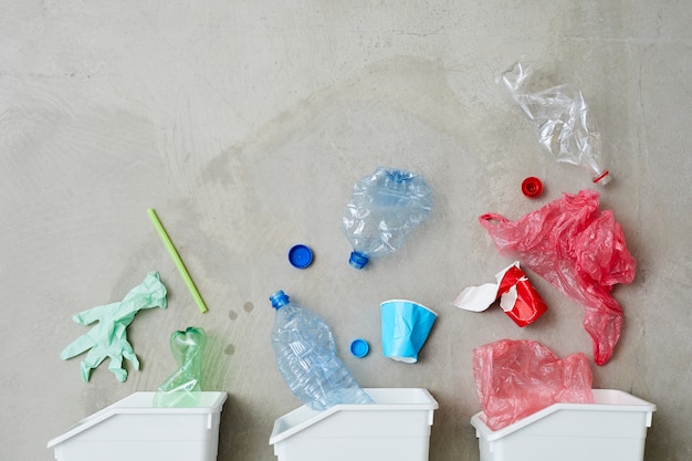 Imagen de tres contenedores de basura con basura clasificada aislado sobre fondo gris