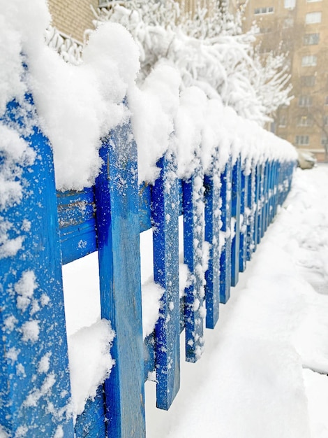 Imagen de una valla azul cubierta de nieve de madera