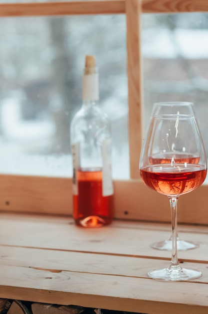 Una imagen vertical de una botella de vino rosado y dos copas.