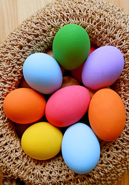 Imagen vertical de una canasta tejida llena de coloridos huevos de Pascua