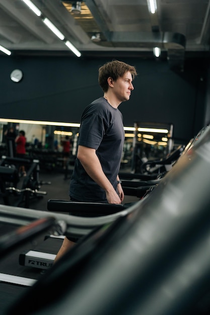 Foto imagen vertical de un deportista principiante haciendo un entrenamiento cardio intensivo para quemar calorías en el gimnasio.