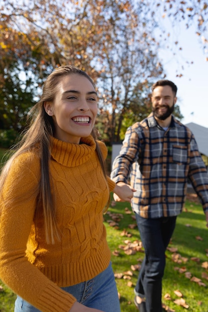 Imagen vertical de una feliz pareja caucásica caminando en el jardín de otoño. Amor, relación, pasar tiempo de calidad juntos.