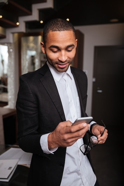 Imagen vertical del hombre africano en traje con teléfono en el hotel