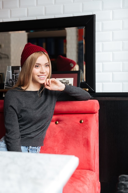 Imagen vertical de joven mujer sentada junto a la mesa