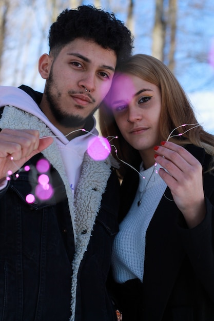 Imagen vertical de una joven pareja comprometida con una corona de Navidad