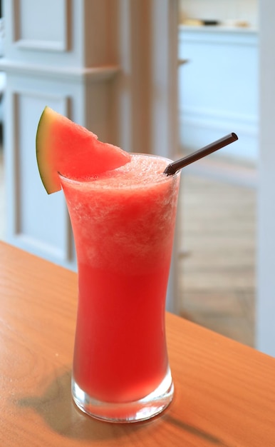 Imagen vertical de un vaso de batido de sandía de carne servido en mesa de madera