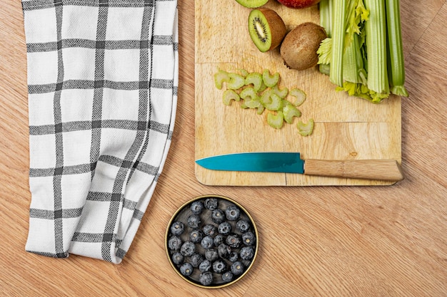Imagen de vista superior de frutas y verduras para hacer jugo de desintoxicación con cuchillo y toalla de cocina