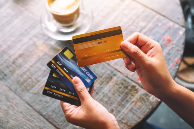 Imagen de la vista superior de una mujer sosteniendo y mostrando tarjetas de crédito